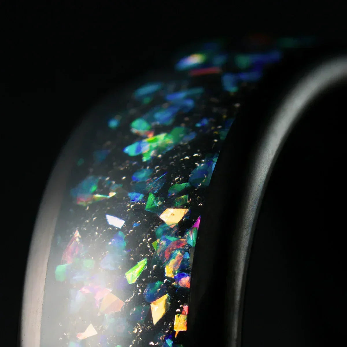 Anillo negro con incrustaciones brillantes de colores, detalle de joyería elegante
