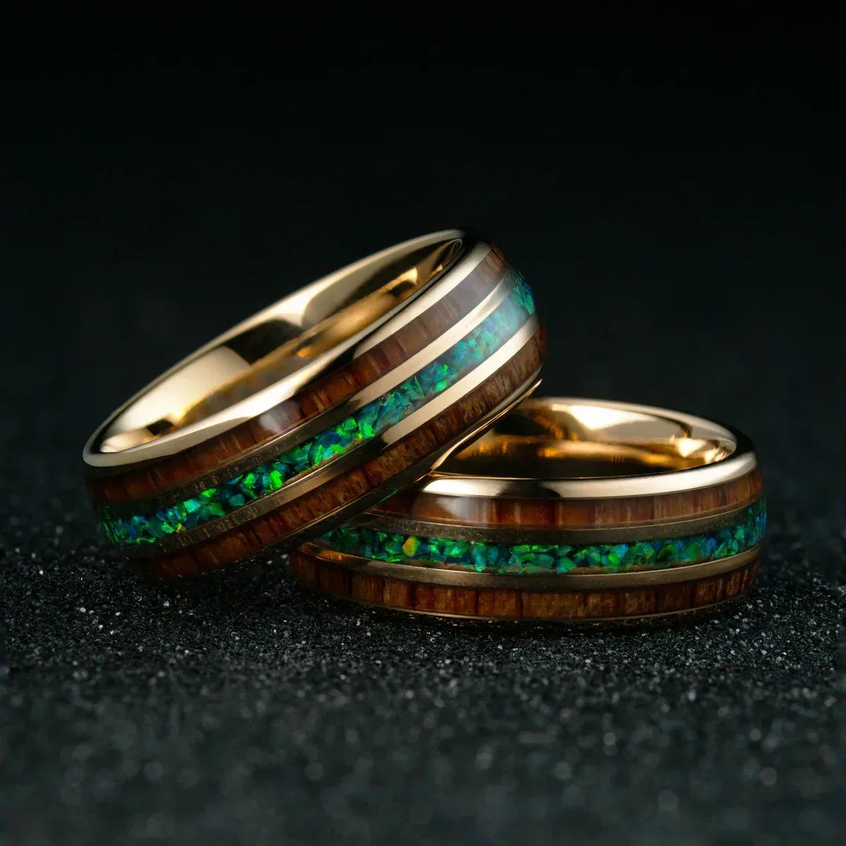 Anillos dorados con incrustaciones de madera y resina verde brillante sobre fondo oscuro