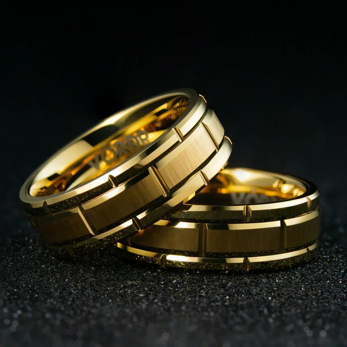 Anillos dorados de acero inoxidable con diseño moderno sobre fondo negro, joyería elegante.