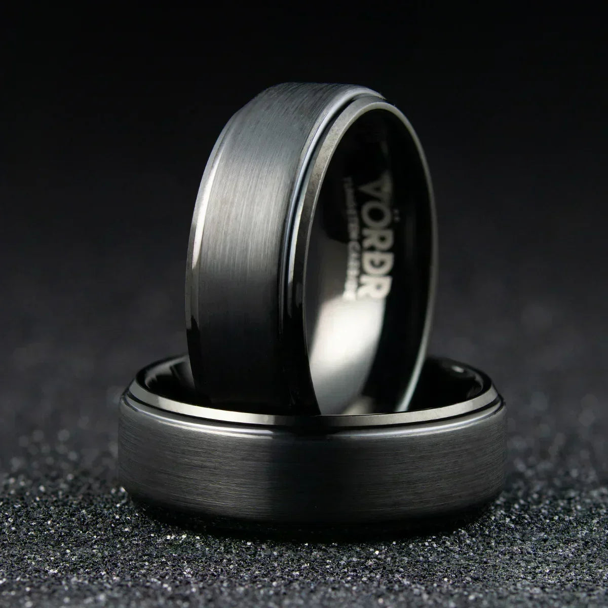 Anillo de acero inoxidable negro mate con acabado cepillado sobre fondo oscuro