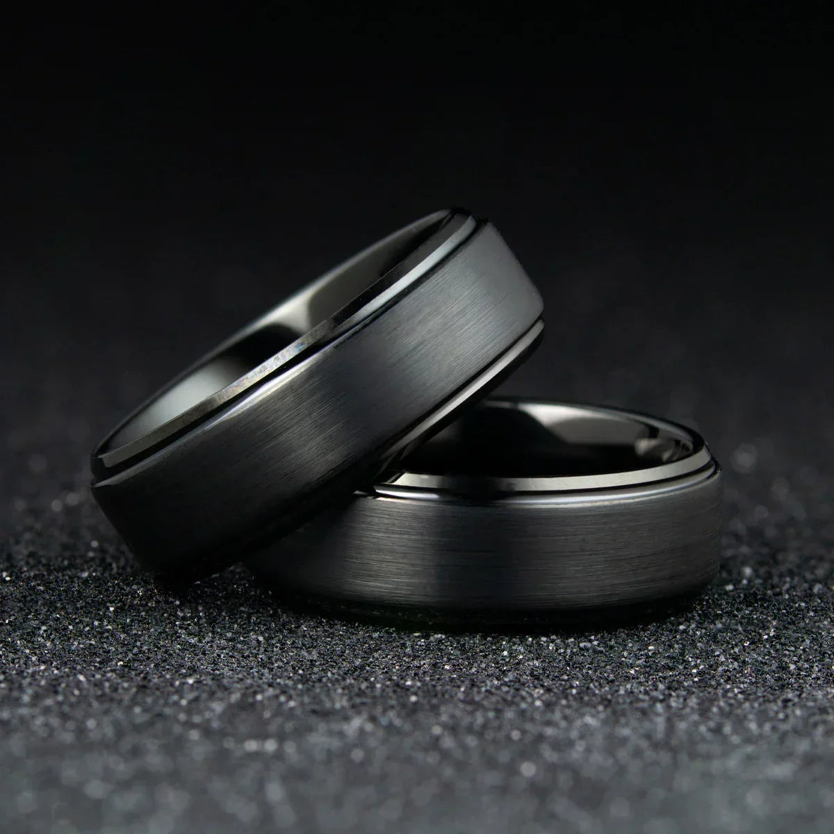 Anillos modernos de tungsteno gris mate sobre fondo oscuro, joyería elegante para hombre