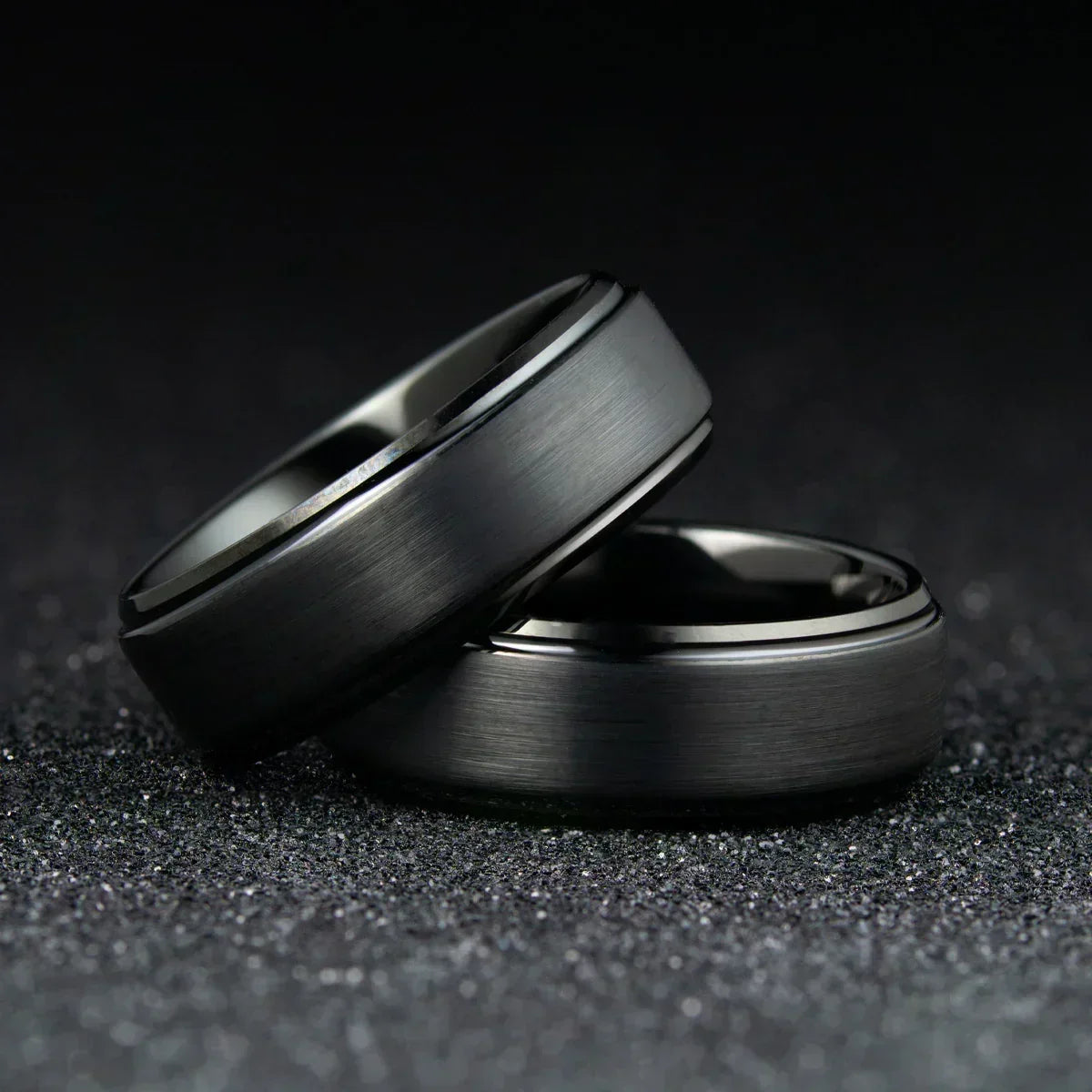 Anillos modernos de tungsteno gris mate sobre fondo oscuro, joyería elegante para hombre