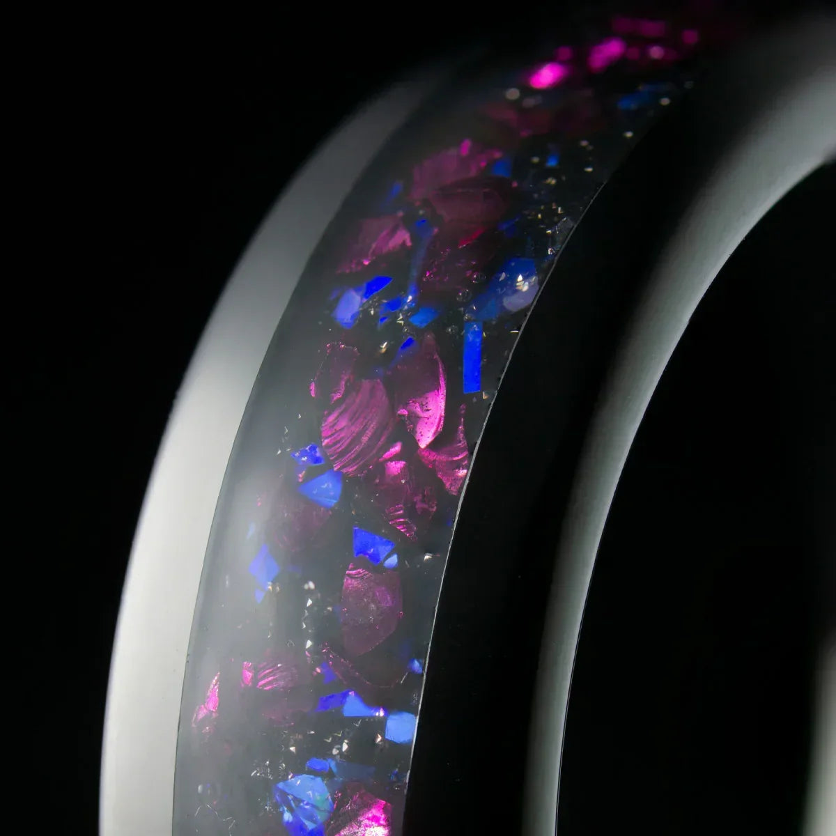 Anillo moderno con incrustaciones de piedras moradas y azules, fondo negro elegante