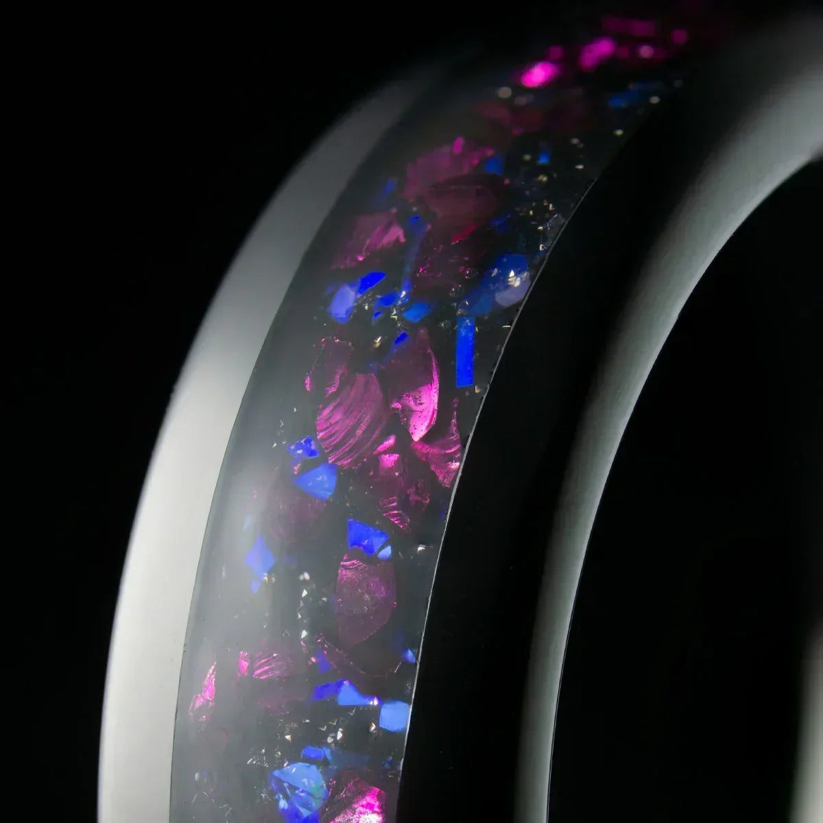 Anillo moderno con incrustaciones de piedras moradas y azules, fondo negro elegante