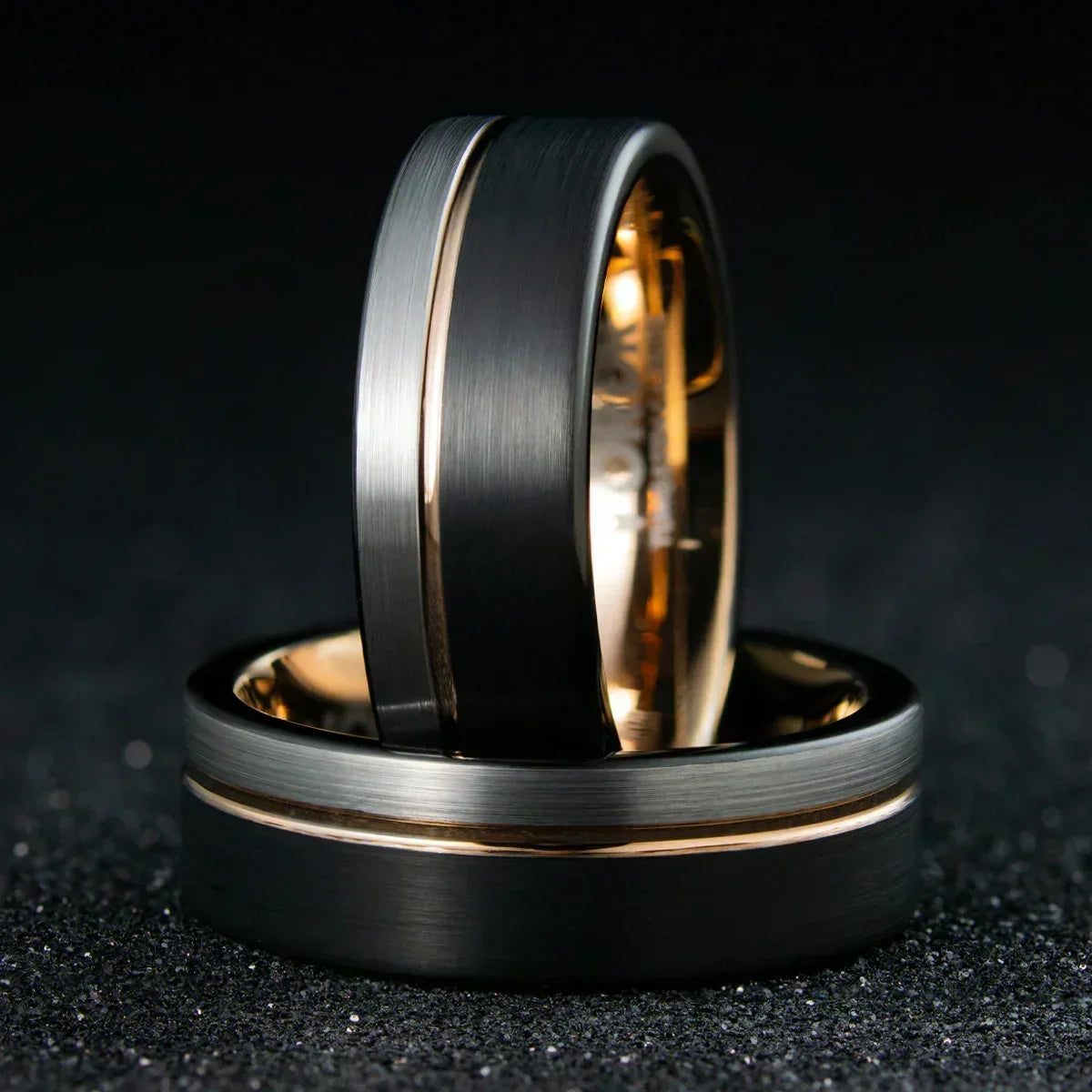 Anillo de acero negro mate y dorado, diseño moderno sobre fondo oscuro, joyería elegante.