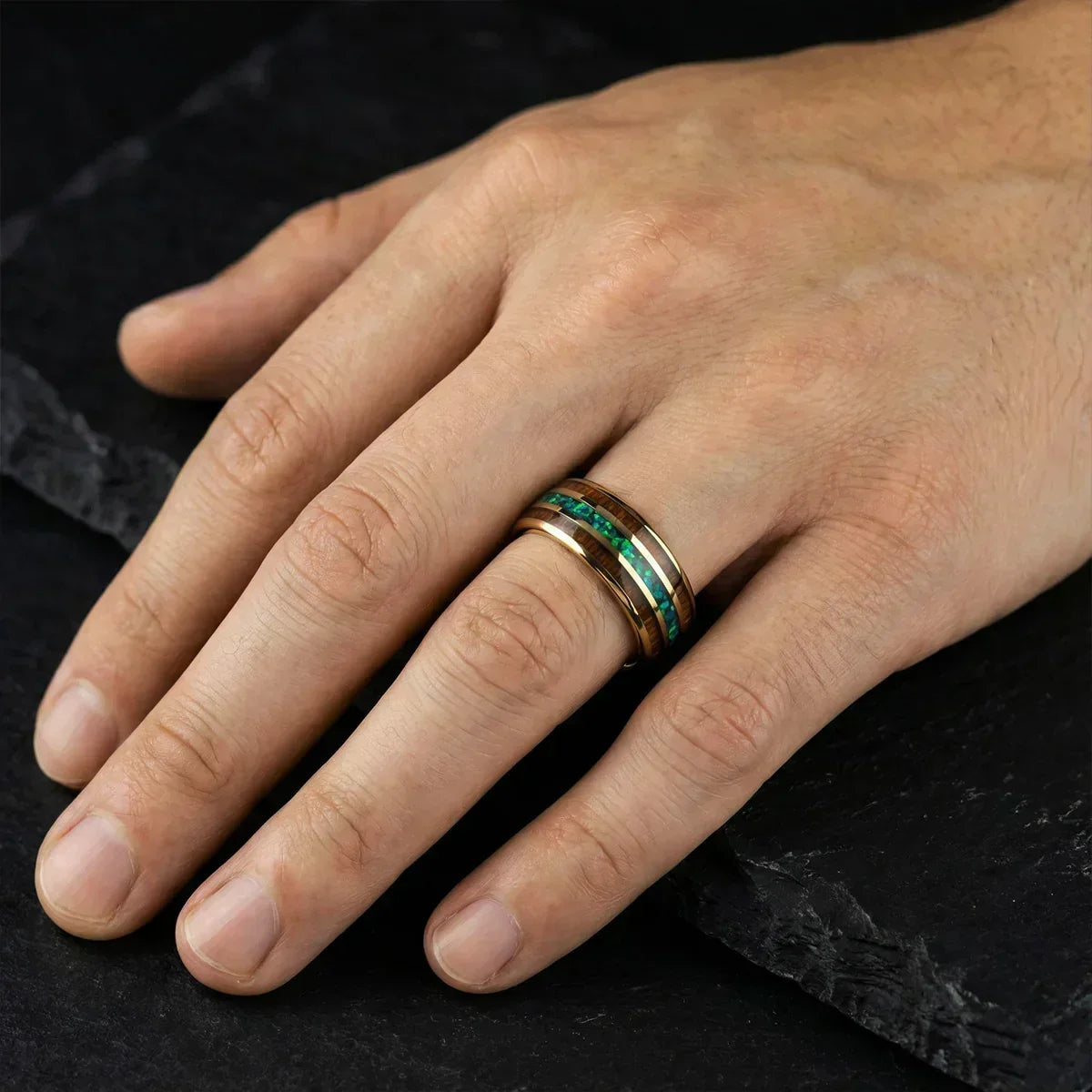 Mano masculina con anillo de lujo dorado y detalles verdes sobre fondo negro elegante