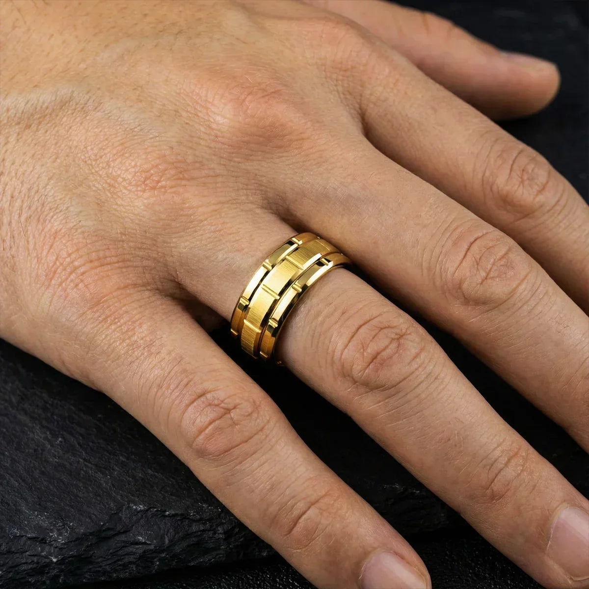 Anillo de acero inoxidable dorado para hombre sobre mano sobre fondo oscuro