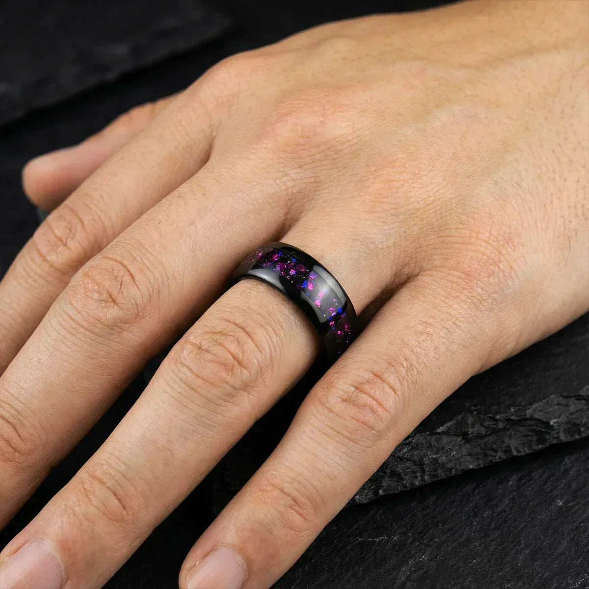 Anillo negro con incrustaciones moradas brillante en dedo, joyería moderna para hombre