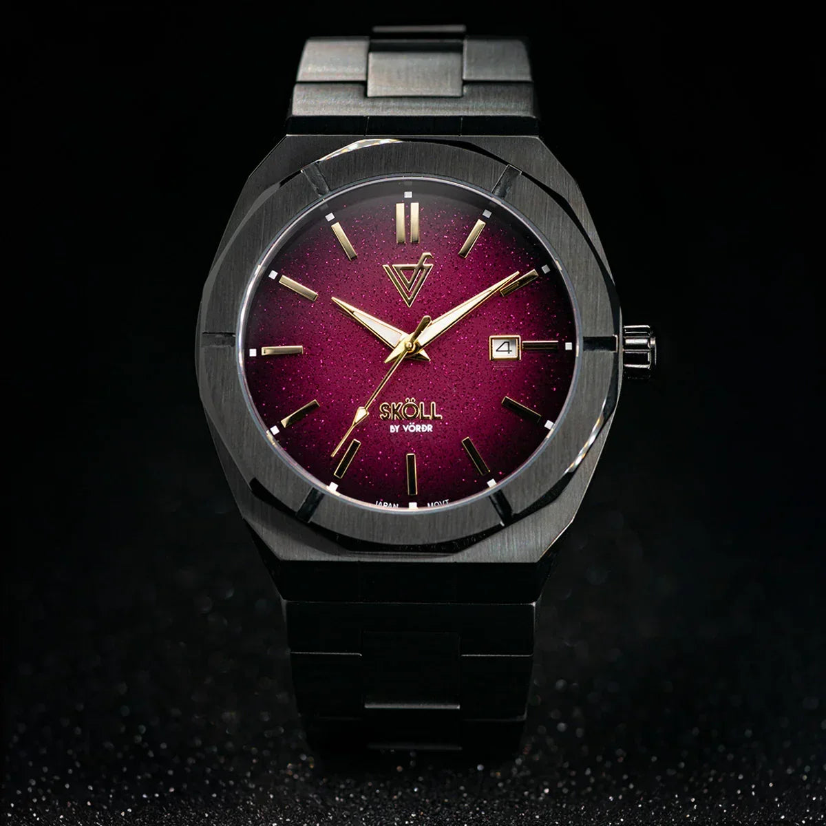 Reloj elegante de acero negro con carátula burdeos y manecillas doradas sobre fondo oscuro