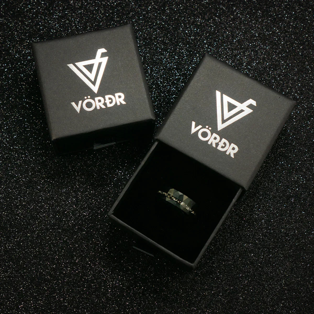 Caja de anillo negra elegante con logotipo en tapa, fondo brillante, joyería premium