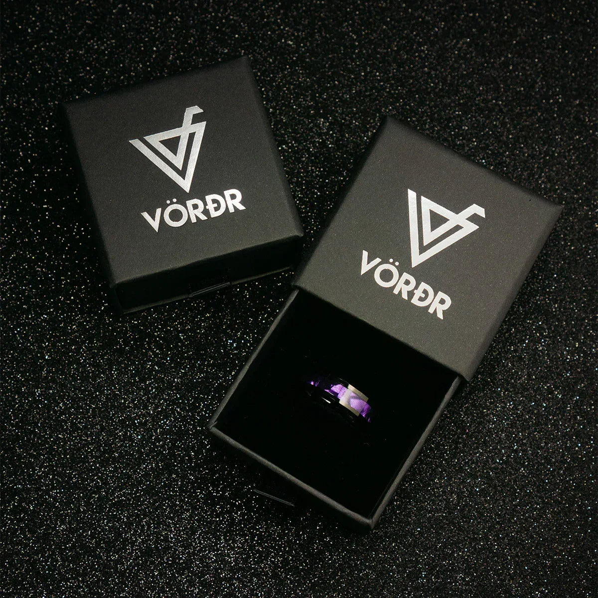Caja negra elegante para anillo o joya con logo plateado y anillo violeta al interior