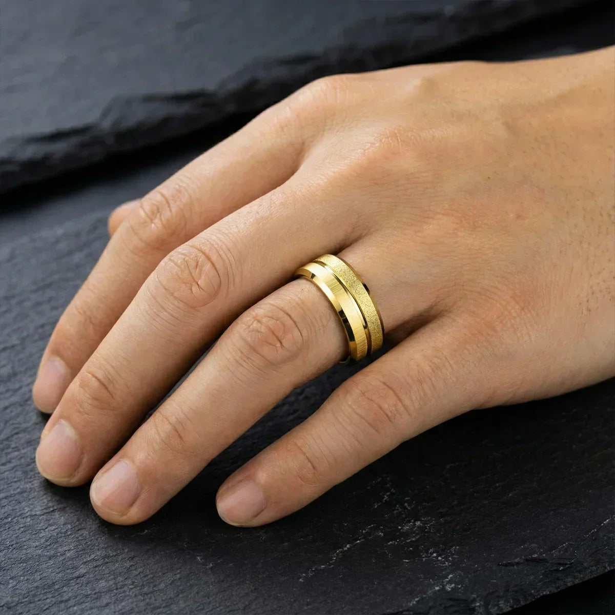 Anillo dorado elegante en mano masculina sobre fondo negro, joyería de lujo para hombres