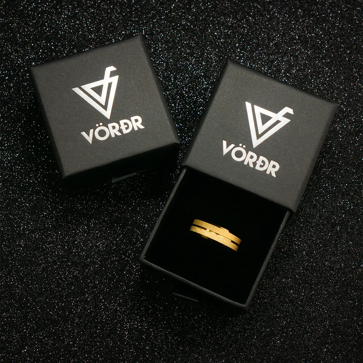 Anillo dorado en caja negra elegante sobre fondo brillante