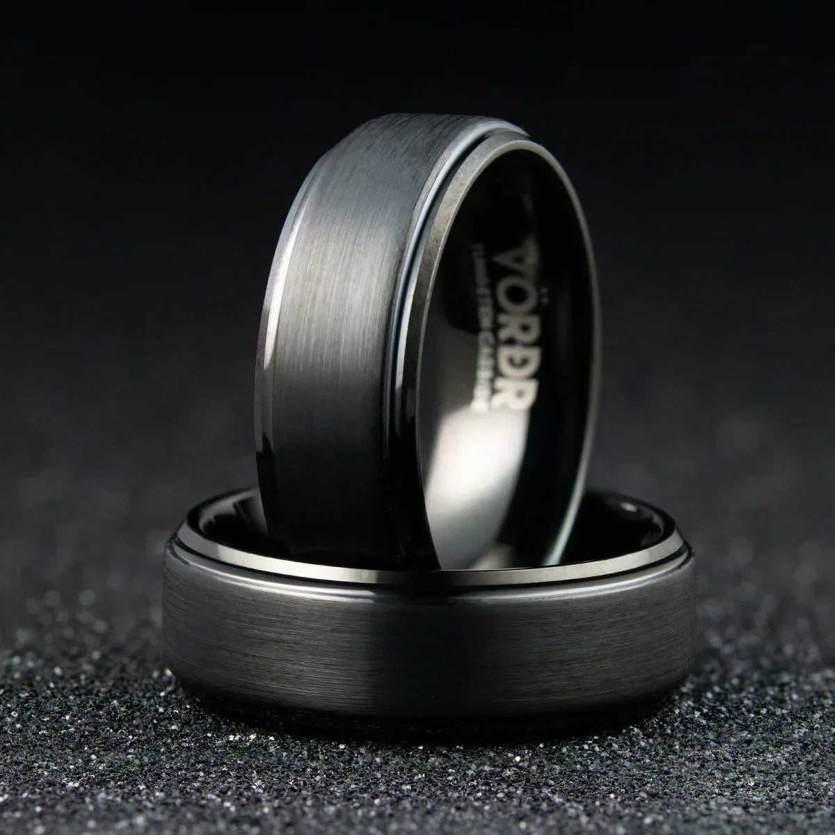 Anillo de acero inoxidable negro mate con acabado cepillado sobre fondo oscuro