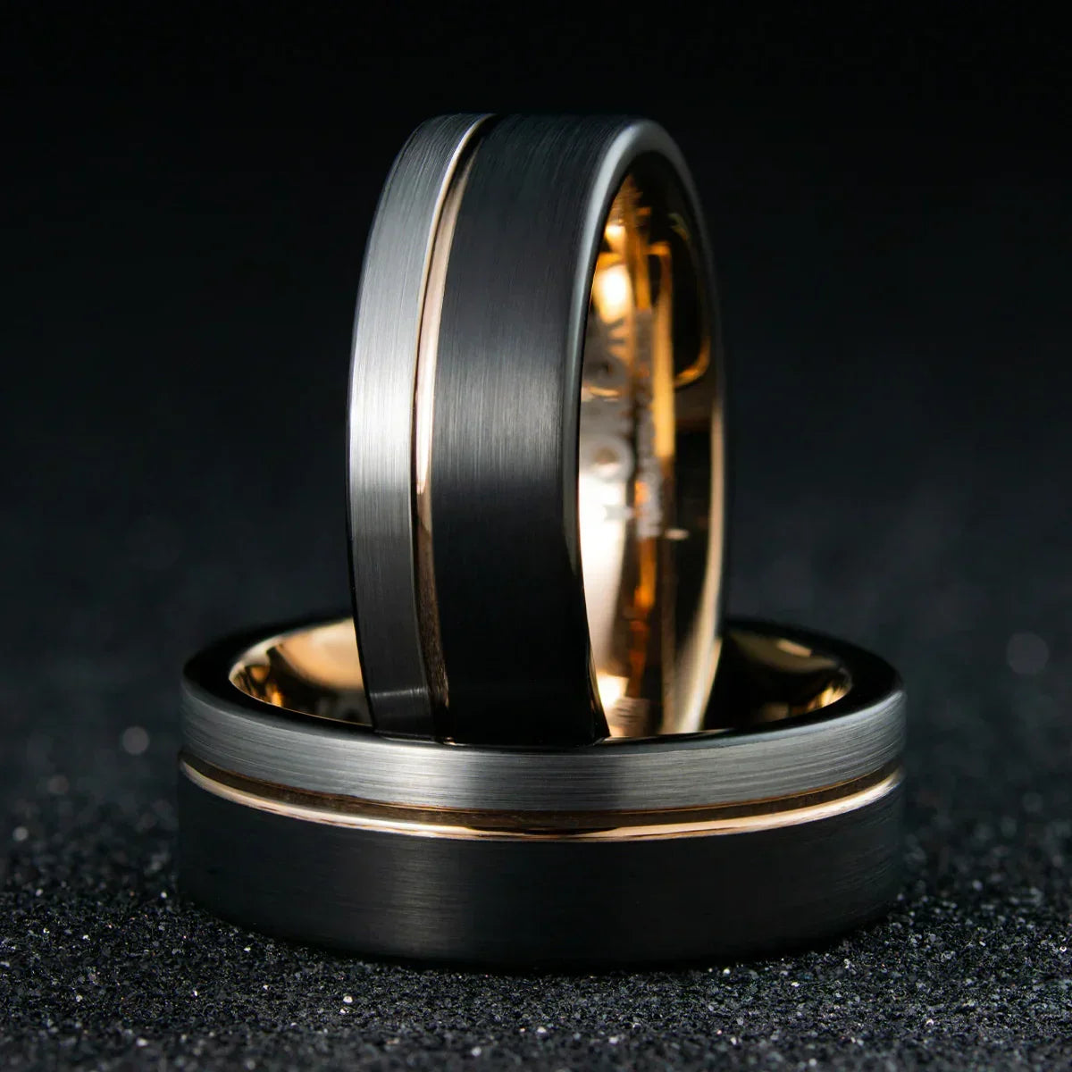 Anillo de acero negro mate y dorado, diseño moderno sobre fondo oscuro, joyería elegante.