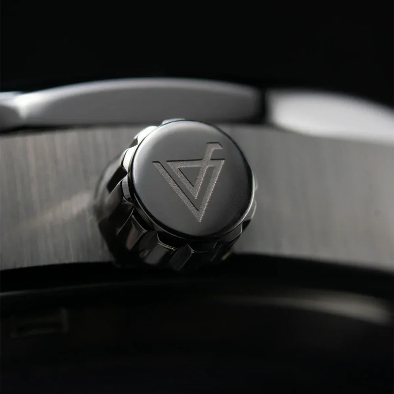 Detalle de la corona de reloj metálica con grabado geométrico moderno en acero inoxidable.