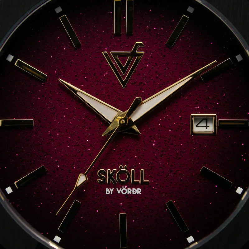 Reloj de pulsera elegante con carátula burdeos, manecillas doradas y marcador de fecha.